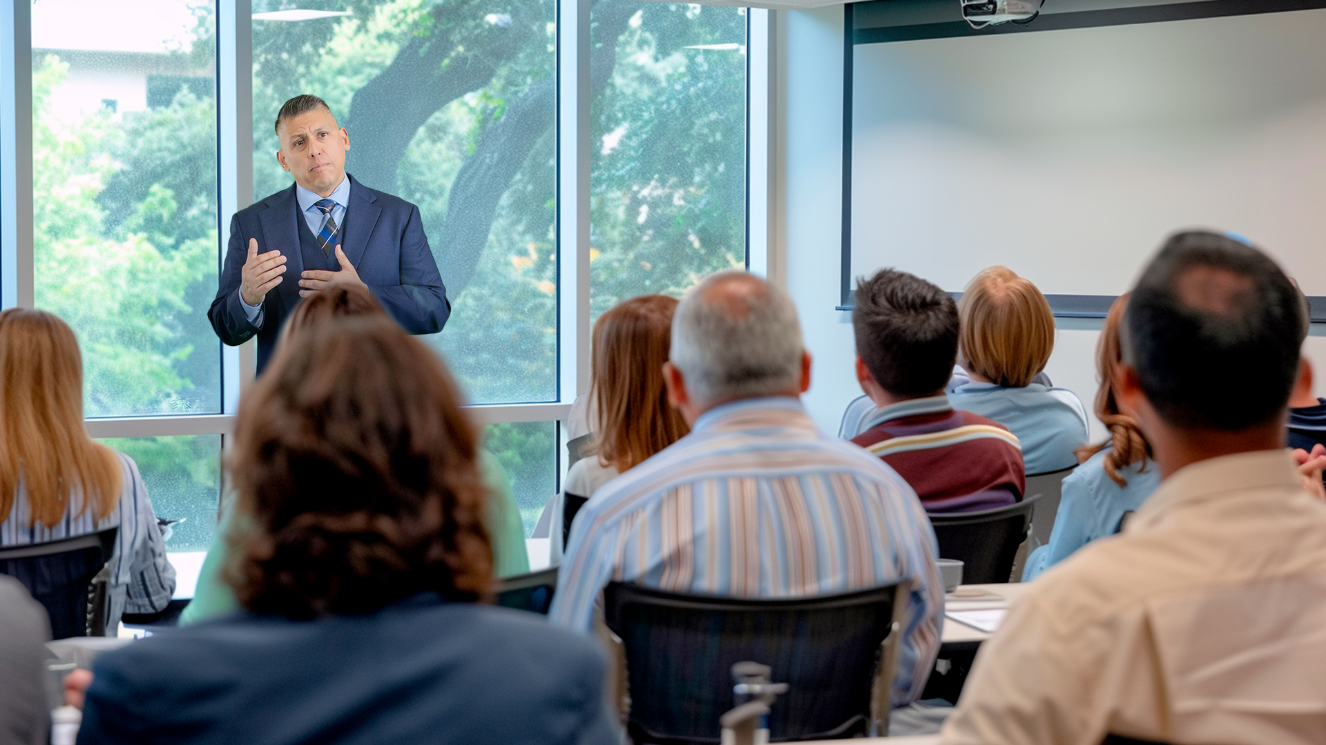 Professional speaker in a navy blue suit presenting to an audience